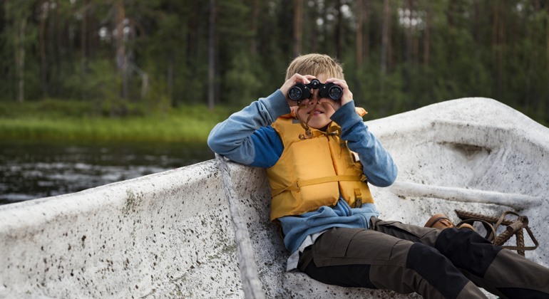 en pojke med en kikare i en roddbåt foto: Johnér